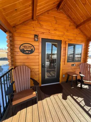 a wooden cabin with two chairs and a door at Private Luxury Log Cabin in the Endless Mountains, Firepit, Farm Charm in Kingsley