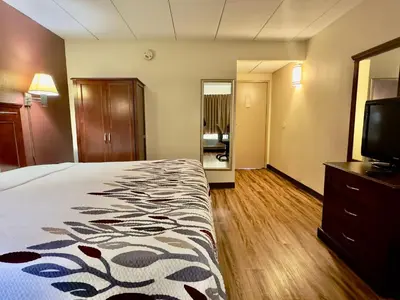 a hotel room with a bed and a flat screen tv at Red Roof Inn Hartford - Vernon in Vernon