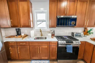 a kitchen with wooden cabinets and a stove and a sink at Apartment in Irvington Unit B in Irvington