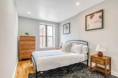 a bedroom with a bed and a dresser and a window at Pent House on Bruckner New Luxe 2BR 2BA King Bed Fast Wi-Fi 15 Mins to Times Square in Mott Haven