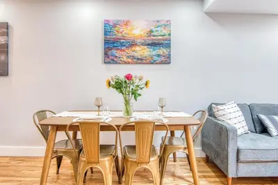 a dining room table with chairs and a vase of flowers at Pent House on Bruckner New Luxe 2BR 2BA King Bed Fast Wi-Fi 15 Mins to Times Square in Mott Haven
