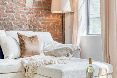 a living room with a white couch and a brick wall at Pent House on Bruckner New Luxe 2BR 2BA King Bed Fast Wi-Fi 15 Mins to Times Square in Mott Haven