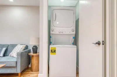 a washer and dryer in a living room with a couch at Pent House on Bruckner New Luxe 2BR 2BA King Bed Fast Wi-Fi 15 Mins to Times Square in Mott Haven