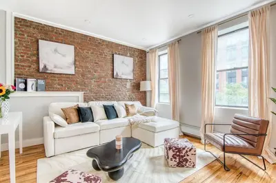 a living room with a couch and a brick wall at Pent House on Bruckner New Luxe 2BR 2BA King Bed Fast Wi-Fi 15 Mins to Times Square in Mott Haven