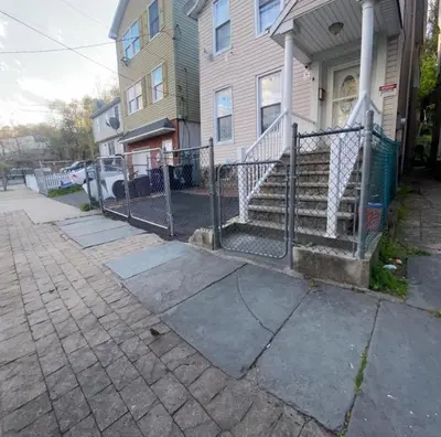 a fence in front of a house with stairs at Spacious Private Room with Private Bath in Paterson