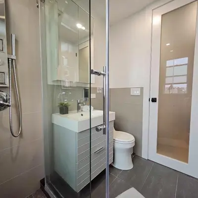 a bathroom with a toilet and a glass shower at Bright Modern 2-bedroom apartment - Prime Astorioa - near subway in Woodside