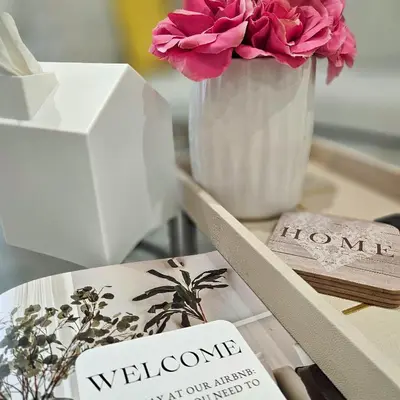 a table with a book and a vase with flowers at Bright Modern 2-bedroom apartment - Prime Astorioa - near subway in Woodside