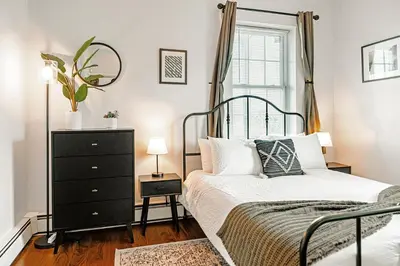 a bedroom with a bed and a dresser and a window at Studio in Little Italy in New Haven