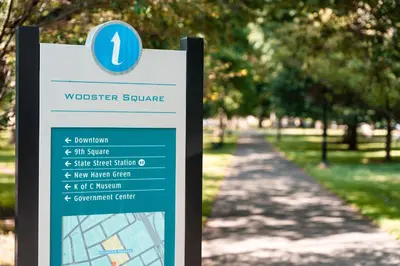 a sign in a park next to a sidewalk at Studio in Little Italy in New Haven