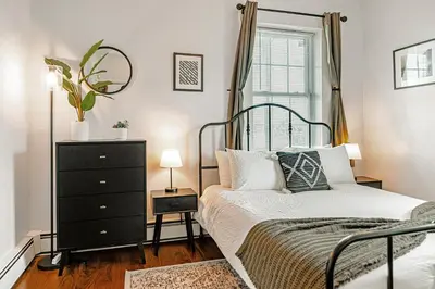 a bedroom with a bed and a dresser and a window at Studio in Little Italy in New Haven