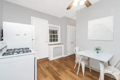 a white kitchen with a table and a stove at Cozy cottage close to NYC in Yonkers