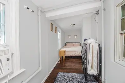 a hallway with a bed in a white room at Cozy cottage close to NYC in Yonkers