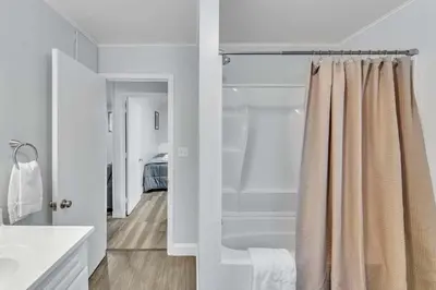 a white bathroom with a shower and a bed at The Main Lineup Apt 4 - All Star Baseball Rentals in Oneonta