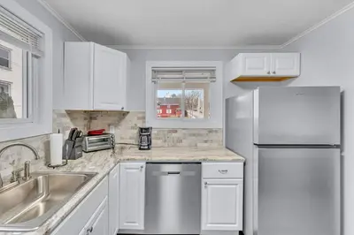 a kitchen with white cabinets and a stainless steel refrigerator at The Main Lineup Apt 4 - All Star Baseball Rentals in Oneonta