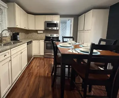 a kitchen with white cabinets and a table with chairs at Cozy Apartment in Watertown
