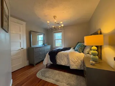 a bedroom with a bed and a dresser and a lamp at Cozy Apartment in Watertown