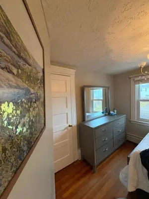 a bedroom with a bed and a dresser and a window at Cozy Apartment in Watertown
