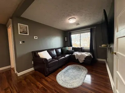 a living room with a leather couch and a window at Cozy Apartment in Watertown