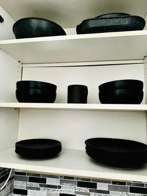 a shelf with black bowls and plates on it at Private Studio Near NYC - Easy Commute & Workspace in Guttenberg
