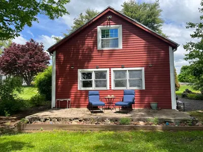 a red house with two chairs and a table at Peaceful Meadow Retreat in Granby