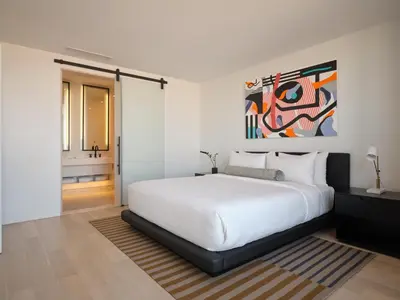 a bedroom with a white bed and a painting on the wall at The William Vale in Brooklyn
