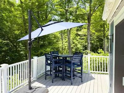 a table and chairs under an umbrella on a porch at Cozy Lake House - Salisbury/Lakeville in Salisbury