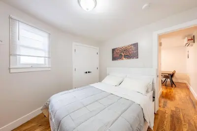 a white bedroom with a bed and a window at Modern 2BR 8 mins to Penn Station with WiFi Laundry in Newark