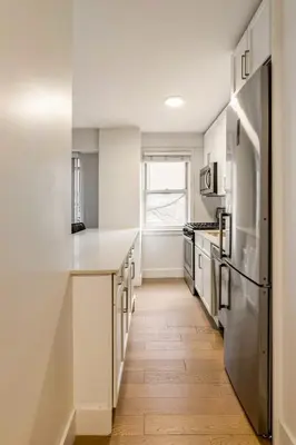 a kitchen with white cabinets and a wooden floor at Piece of mind in Harlem in New York
