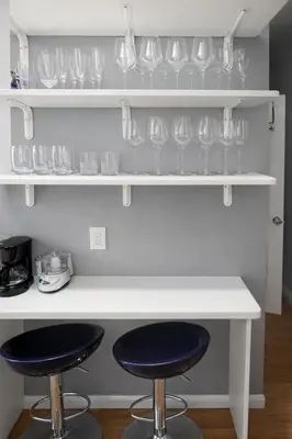 a kitchen with two bar stools and glasses on shelves at Room in a 2 Bedrooms Apartament Long Island City, Kitchen and Bathroom shared with very nice host in New York