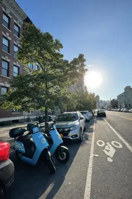 a blue scooter parked next to a row of parked cars at Room in a 2 Bedrooms Apartament Long Island City, Kitchen and Bathroom shared with very nice host in New York