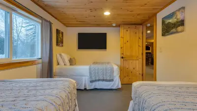 a bedroom with two beds and a flat screen tv at Mins to Hunter Mountain • Sleeps 36 • Pool Spa Games Bar Cozy Peaks Lodge by AvantStay in Tannersville