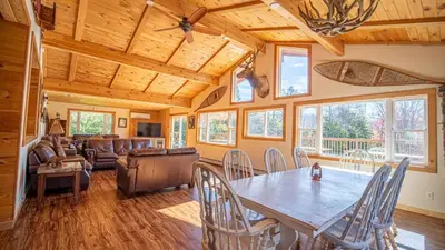 a dining room and living room with a table and chairs at Mins to Hunter Mountain • Sleeps 36 • Pool Spa Games Bar Cozy Peaks Lodge by AvantStay in Tannersville