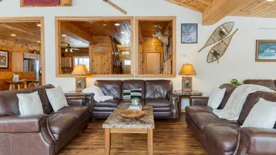 a living room with leather couches and a table at Mins to Hunter Mountain • Sleeps 36 • Pool Spa Games Bar Cozy Peaks Lodge by AvantStay in Tannersville