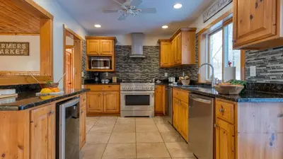 a kitchen with wooden cabinets and stainless steel appliances at Scenic Catskills Retreat • Pool Hot Tub Game Room Lake Views Mountainview Estate by AvantStay in Jewett