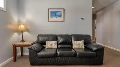 a black leather couch sitting in a living room at Scenic Catskills Retreat • Pool Hot Tub Game Room Lake Views Mountainview Estate by AvantStay in Jewett