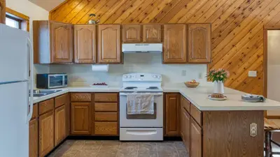 a kitchen with wooden cabinets and a white stove top oven at Scenic Catskills Retreat • Pool Hot Tub Game Room Lake Views Mountainview Estate by AvantStay in Jewett