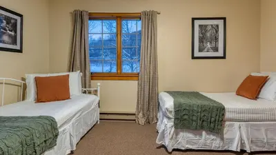 two beds in a room with a window at Scenic Catskills Retreat • Pool Hot Tub Game Room Lake Views Mountainview Estate by AvantStay in Jewett