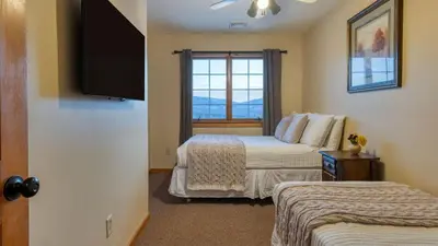 a bedroom with two beds and a flat screen tv at Scenic Catskills Retreat • Pool Hot Tub Game Room Lake Views Mountainview Estate by AvantStay in Jewett