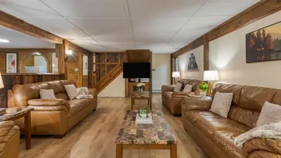 a living room with leather couches and a tv at Sleeps 40 • Heated Pool • Hot Tub • Fire Pit • Game Room Brookside Mountain Retreat by AvantStay in Stephentown