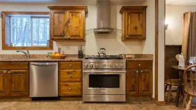 a kitchen with wooden cabinets and a stainless steel stove at Sleeps 40 • Heated Pool • Hot Tub • Fire Pit • Game Room Brookside Mountain Retreat by AvantStay in Stephentown
