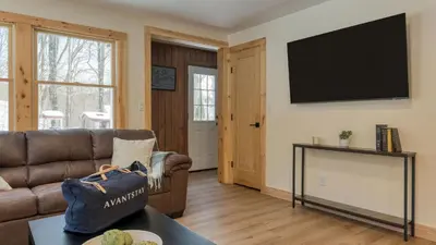 a living room with a couch and a flat screen tv at Sleeps 40 • Heated Pool • Hot Tub • Fire Pit • Game Room Brookside Mountain Retreat by AvantStay in Stephentown