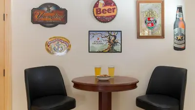 two chairs and a table in a room with beer signs at Sleeps 40 • Heated Pool • Hot Tub • Fire Pit • Game Room Brookside Mountain Retreat by AvantStay in Stephentown