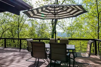 a table and chairs on a deck with an umbrella at NEW! Montview Chalet - Hot Tub, Sauna, EV, Views in East Stroudsburg