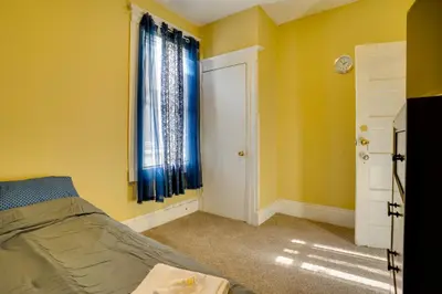 a bedroom with yellow walls and a bed with blue curtains at Easy City Commuting! Walkable Newark Duplex in Newark