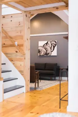 a living room with a staircase and a couch at Rustic Luxe Creekside Retreat with Hot Tub and Fire Pit, Minutes From Hudson in Hudson