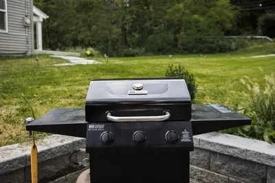 a grill sitting on a table in a yard at Rustic Luxe Creekside Retreat with Hot Tub and Fire Pit, Minutes From Hudson in Hudson