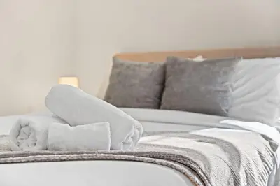 a white bed with a pile of towels on it at Park Hamilton House 3B2B Modern Apt Mins to NYC in Jersey City