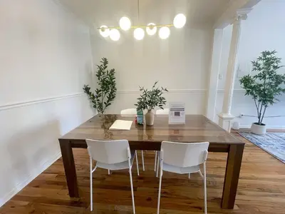 a dining room with a wooden table and white chairs at Park Hamilton House 3B Top Floor Apt Mins to NYC in Jersey City