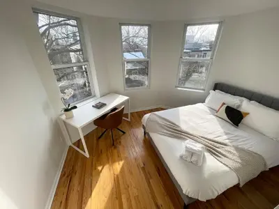 a bedroom with a bed and a desk and windows at Park Hamilton House 3B Top Floor Apt Mins to NYC in Jersey City