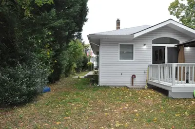 a white house with a porch and a yard at Family-Friendly Retreat With Trampoline & Grill in Locust Valley